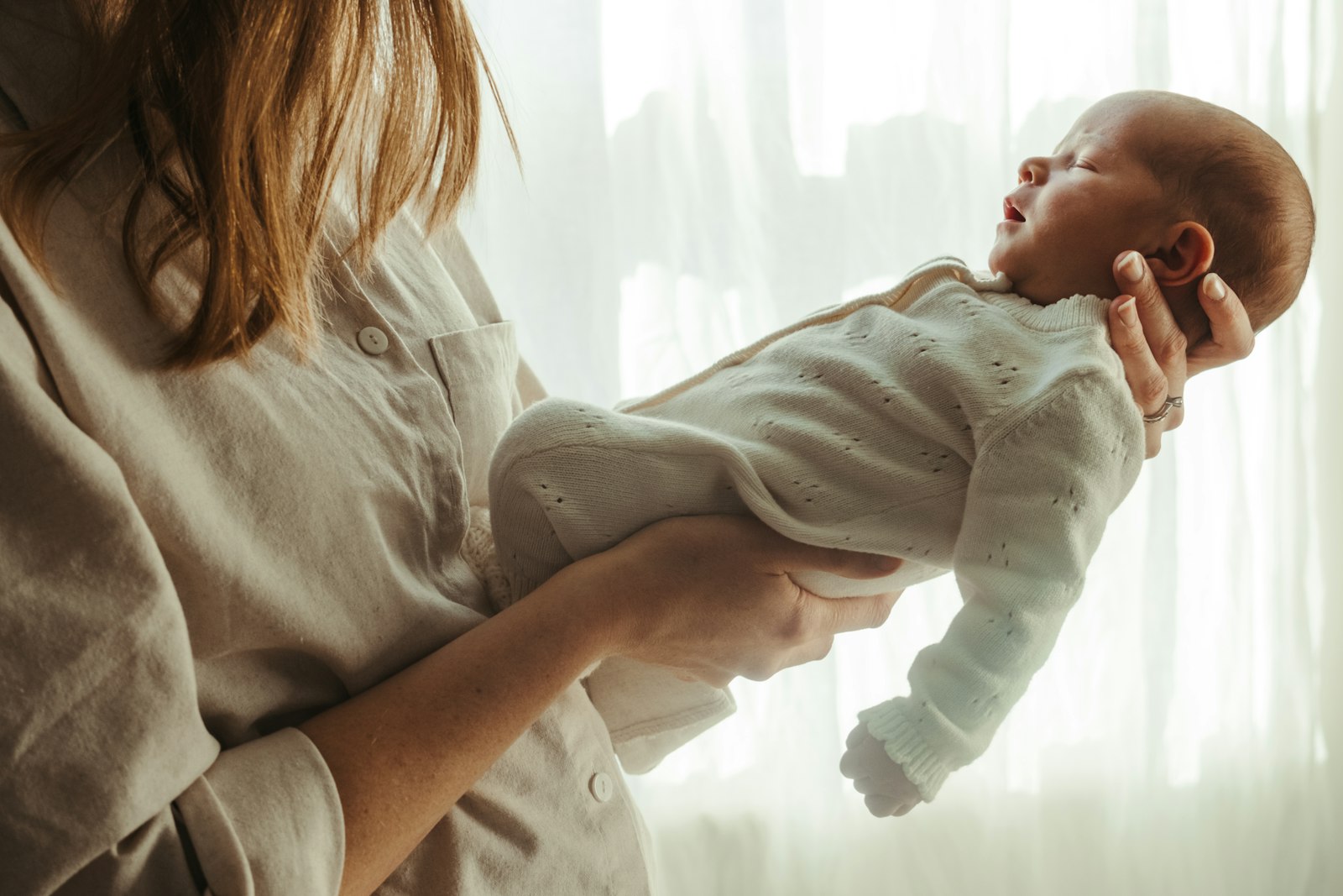 Une mère tient son nouveau-né près d'une fenêtre